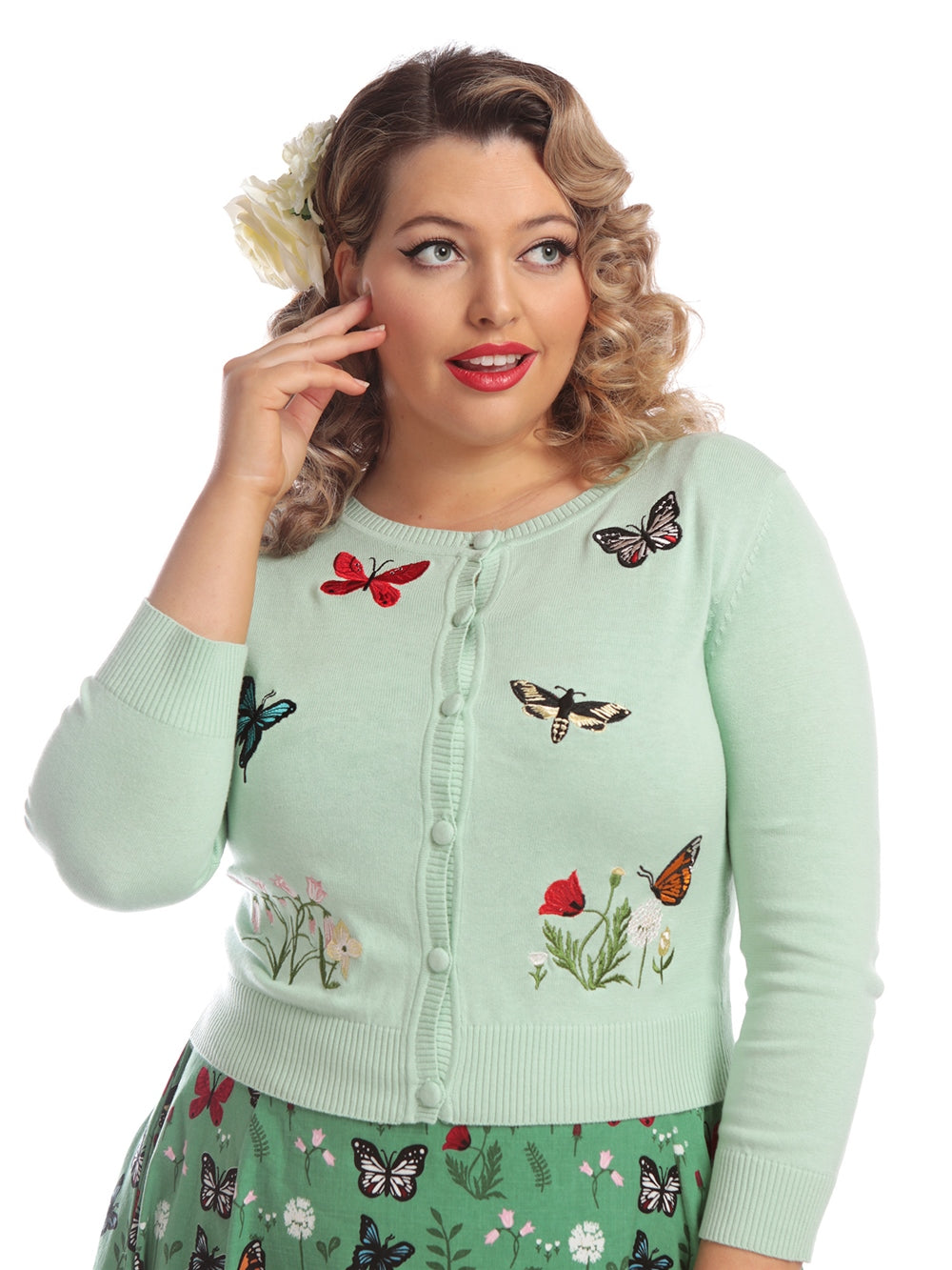 pretty model gazes into the distance while wearing a mint green cardigan with colourful butterflies and flowers embroidered on the front