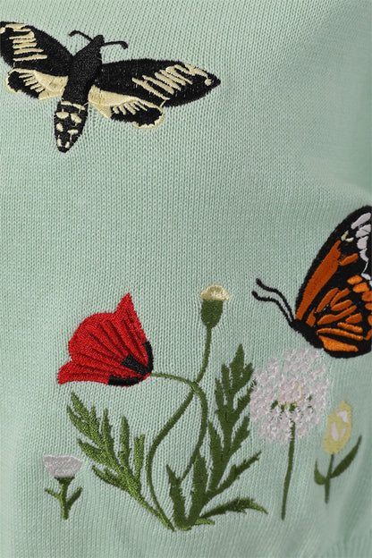 Close up of embroidered red admiral butterfly on an embroidered dandelion amongst other flowers 