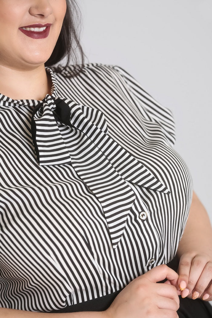 Close up view of the pussybow tie neck and button front of the Humbug blouse by Hell Bunny, worn by a dark haired model with deep red lipstick. 