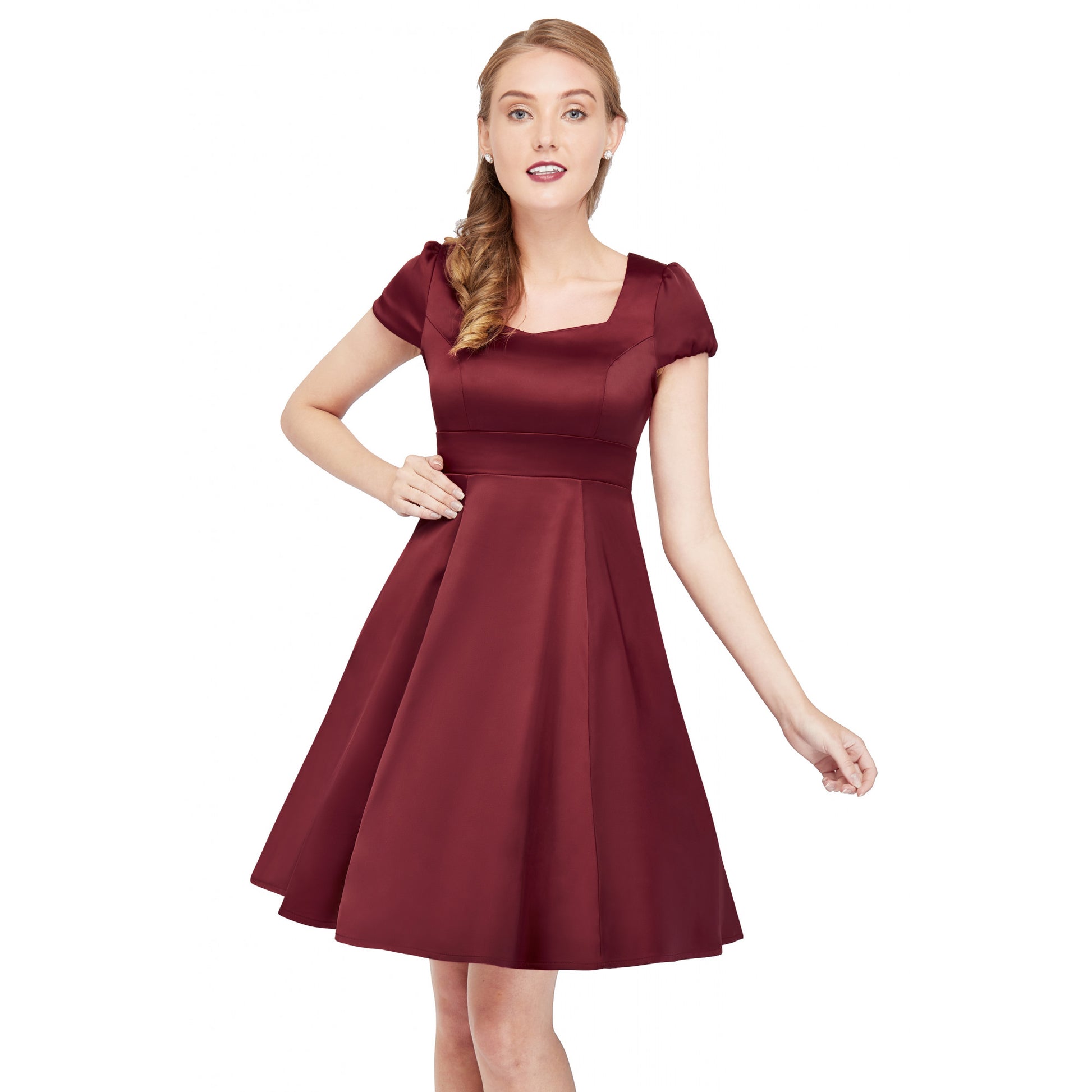 Smiling woman with blonde hair standing with her hand on her hip. She is wearing the Claudia dress in burgundy satin by Dolly and Dotty.