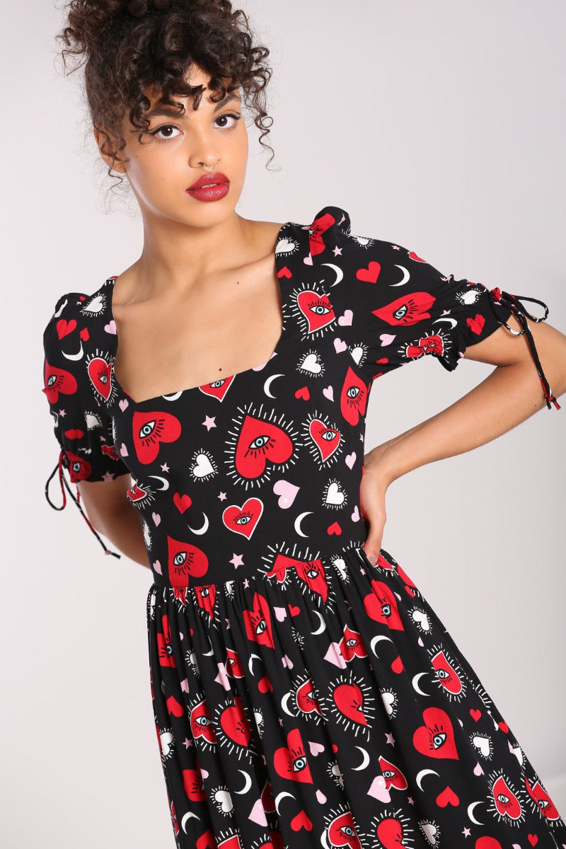 Brown eyed woman with red lipstick standing with one hand on her hip wearing the Kate Heart Maxi Dress by Hell Bunny