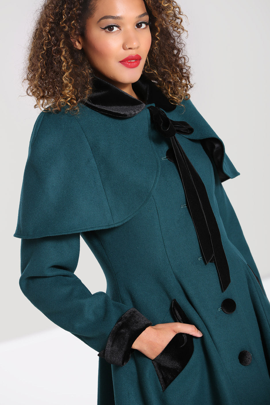 Beautiful curly haired model wearing a vintage green coat with cape 