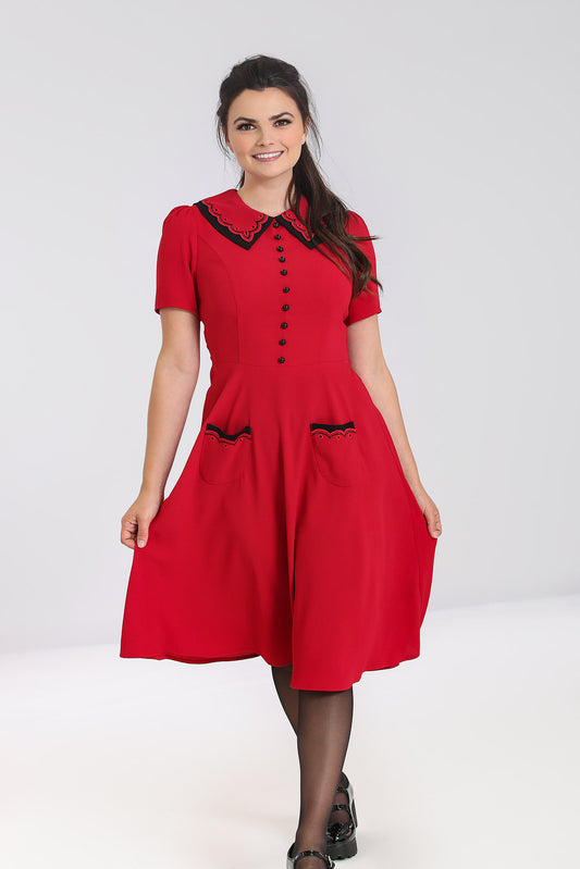 Smiling girl with a ponytail wearing a red dress with black details on the collar and front pockets