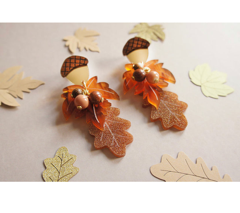 Paper leaves scattered around the Acorn and Autumn leaves earrings.