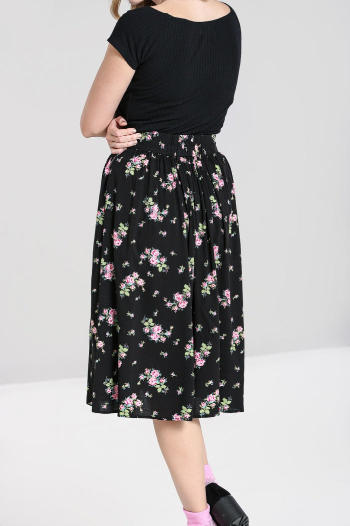 Close up side shot of a woman wearing a black casual t-shirt and a black skirt with an all over floral print