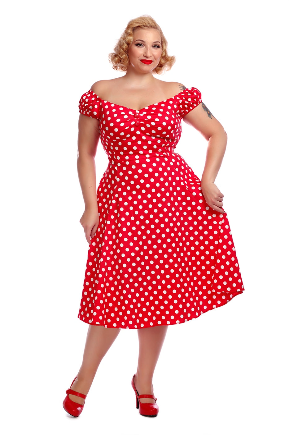 vintage pin up blonde model wearing an off the shoulder red md length dress wit white polka dots