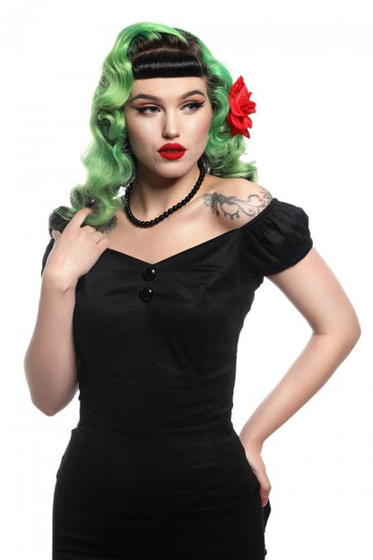 Elegant woman with red lipstick and red hair flower wearing the black Dolores top standing with one hand on her hip