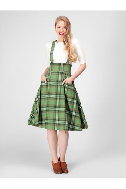 Happy smiling blonde girl standing with her hands in the pockets of a green checked swing skirt