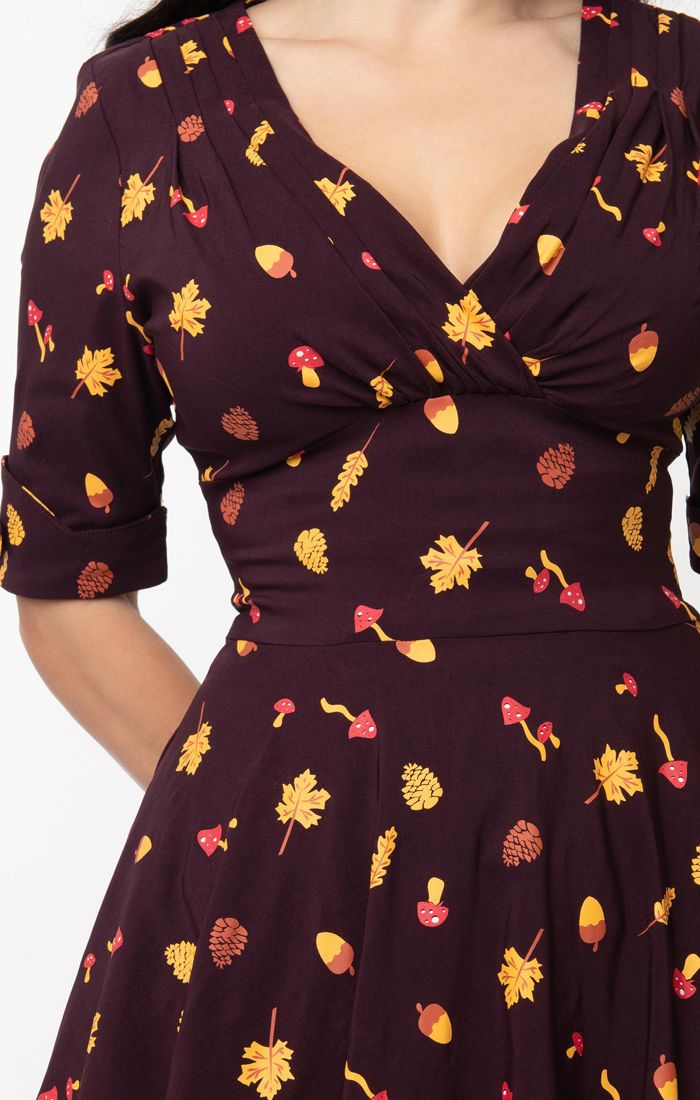 Close up of vintage inspired deep purple dress with Autumnal print, wide waist band and elegant 3/4 length sleeves