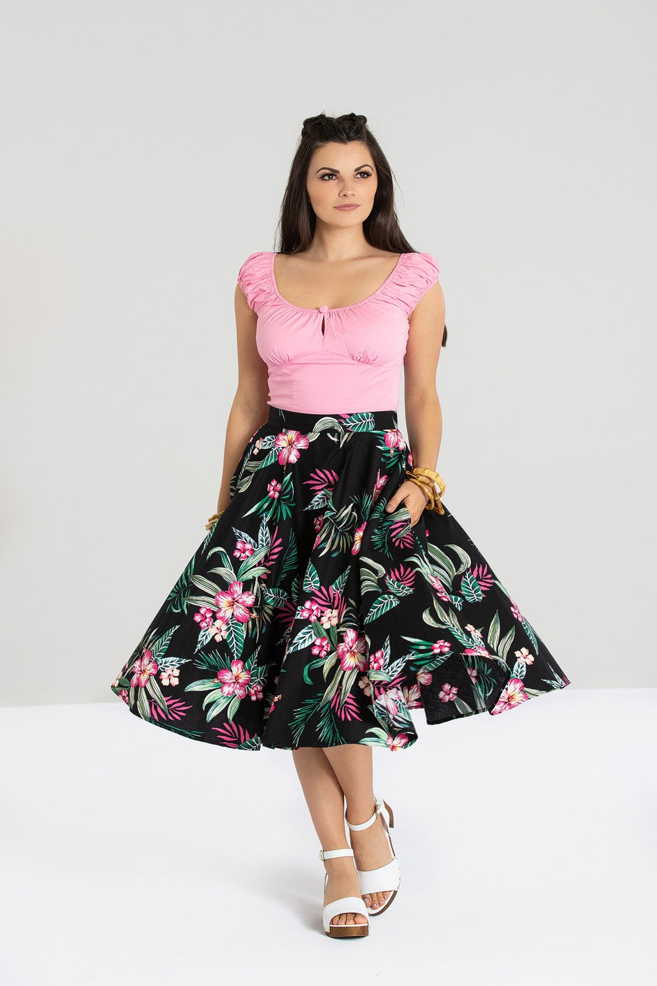 Dark haired girl wearing a short sleeve pink top and pink and black floral print skirt 