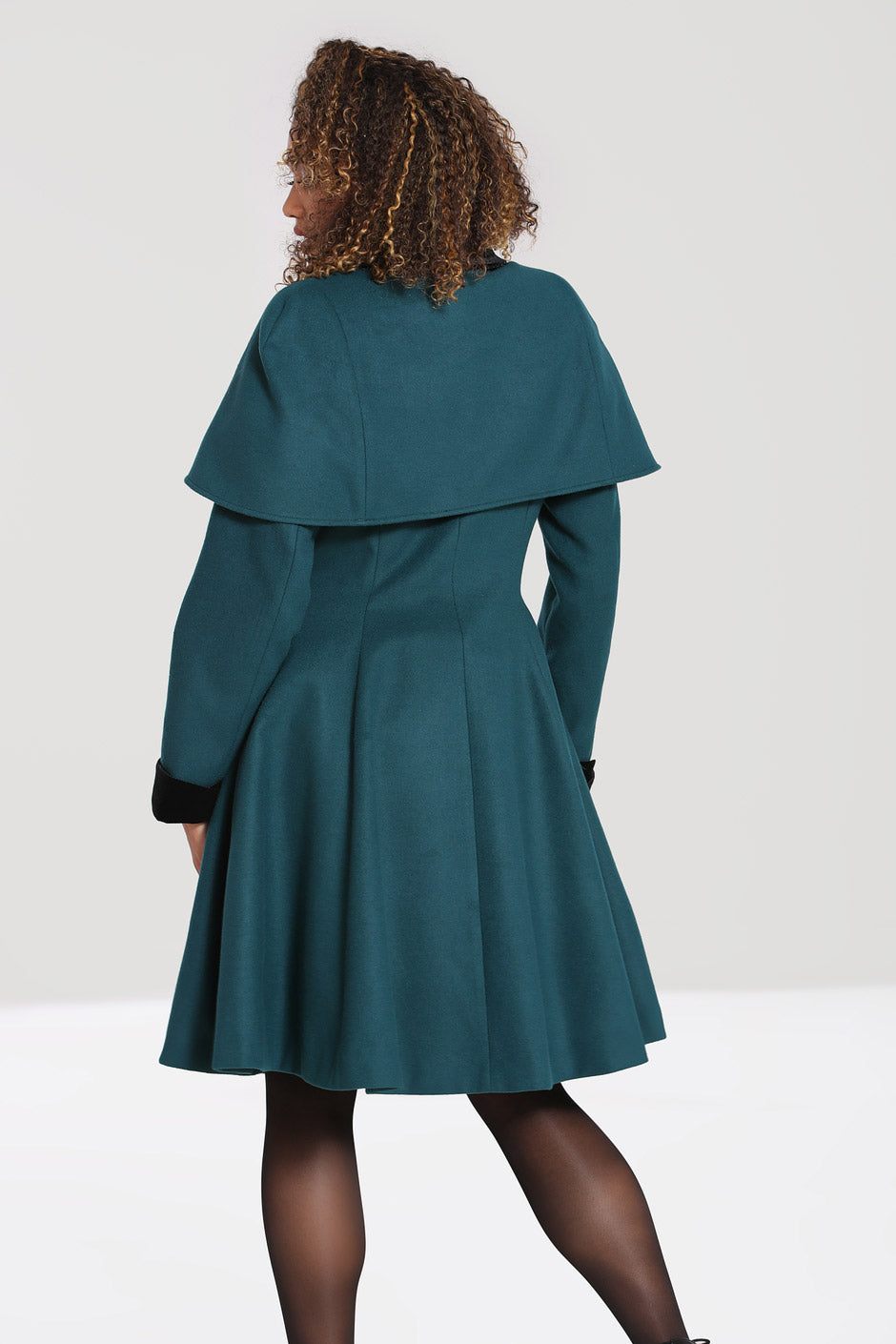 Model showing off the back of her green vintage coat and matching cape