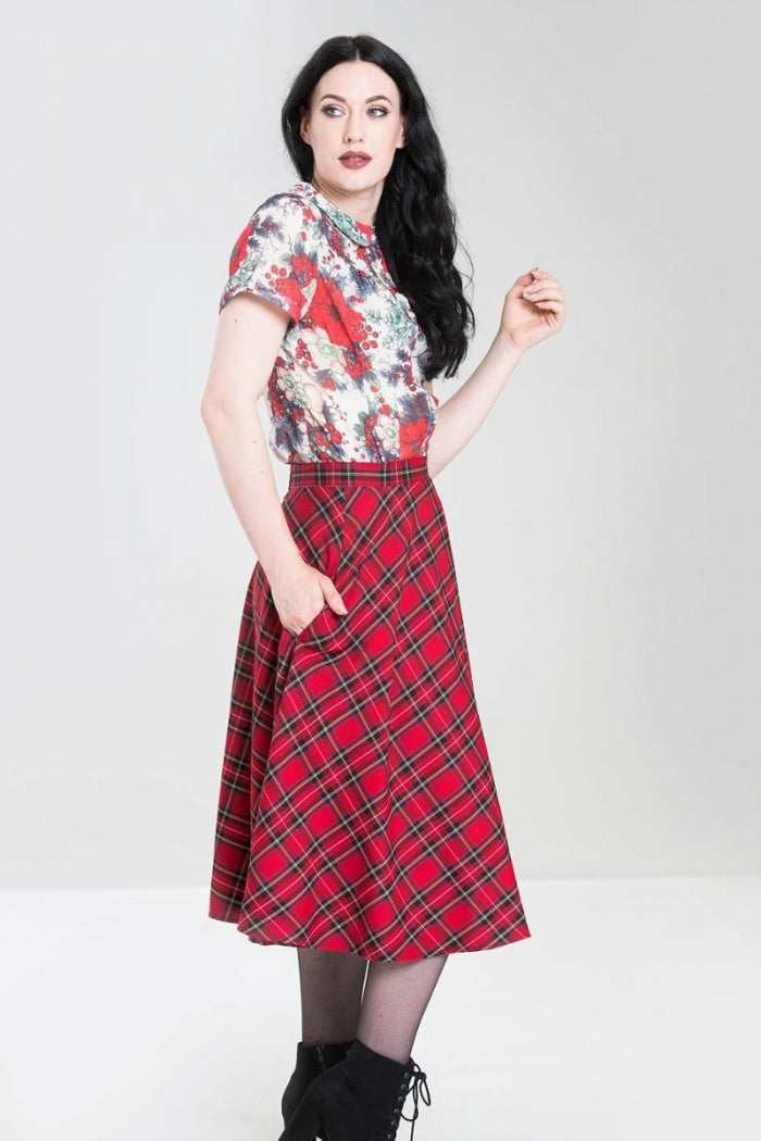 Model wearing a blouse and red tartan 50s style skirt standing with one hand in her skirt pocket