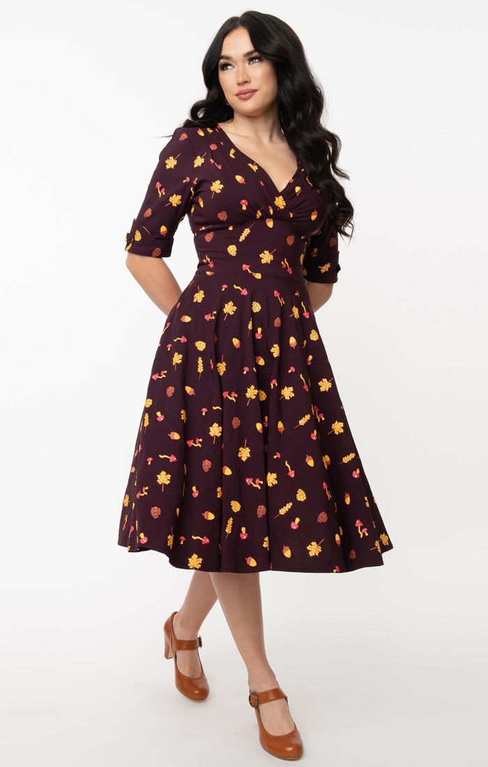 Beautiful girl  in natural makeup wearing a 50s inspired woodland print dress in a deep shade of purple  and brown high heel shoes with buckles.