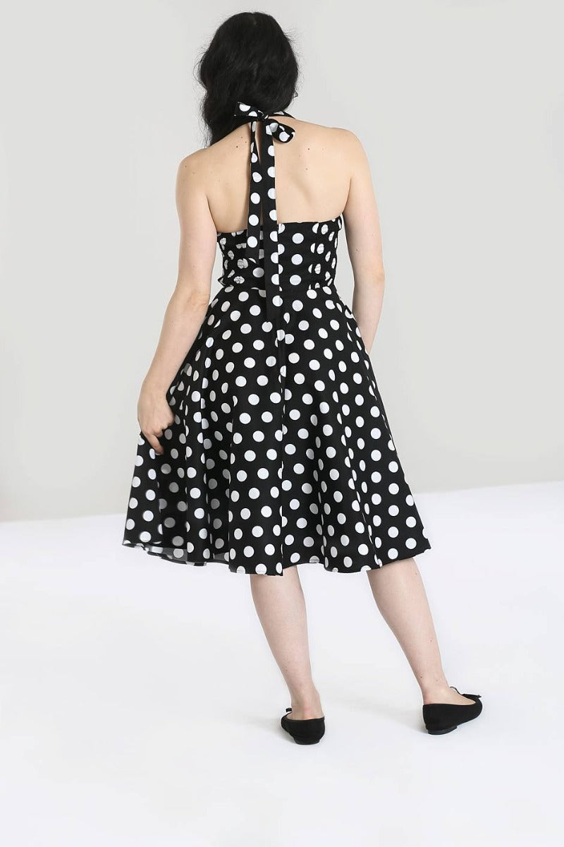 Dark haired girl facing away from the camera wearing a halterneck black dress with large white polka dots 