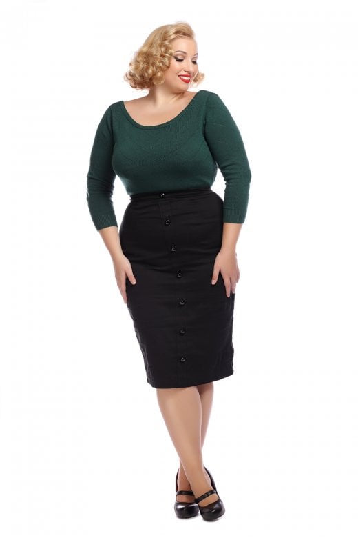 Blonde woman with a radiant smile wearing the black Bettina pencil skirt, black mary jane shoes and a green jumper