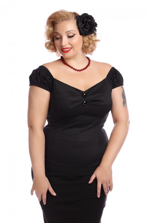 Woman with blonde hair smiling standing with her hands on her thighs looking down wearing a black hair flower, bead necklace and the black Dolores top by Collectif