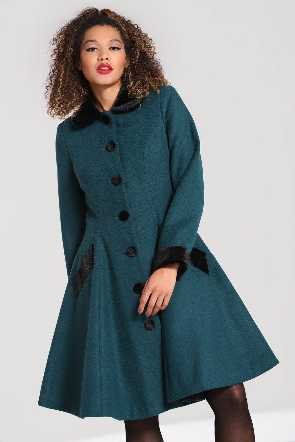 Curly haired vintage woman wearing a dark green coat with black buttons, collar and cuffs