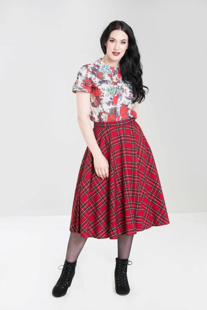 Dark haired model wearing a floral blouse, red tartan skirt and black laceup boots
